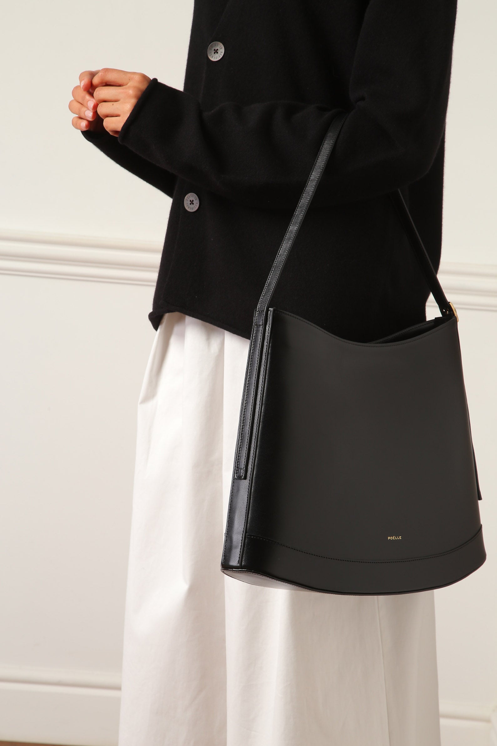 Luxury minimalist sculptural bag by Poelle Atelier in black leather worn over shoulder