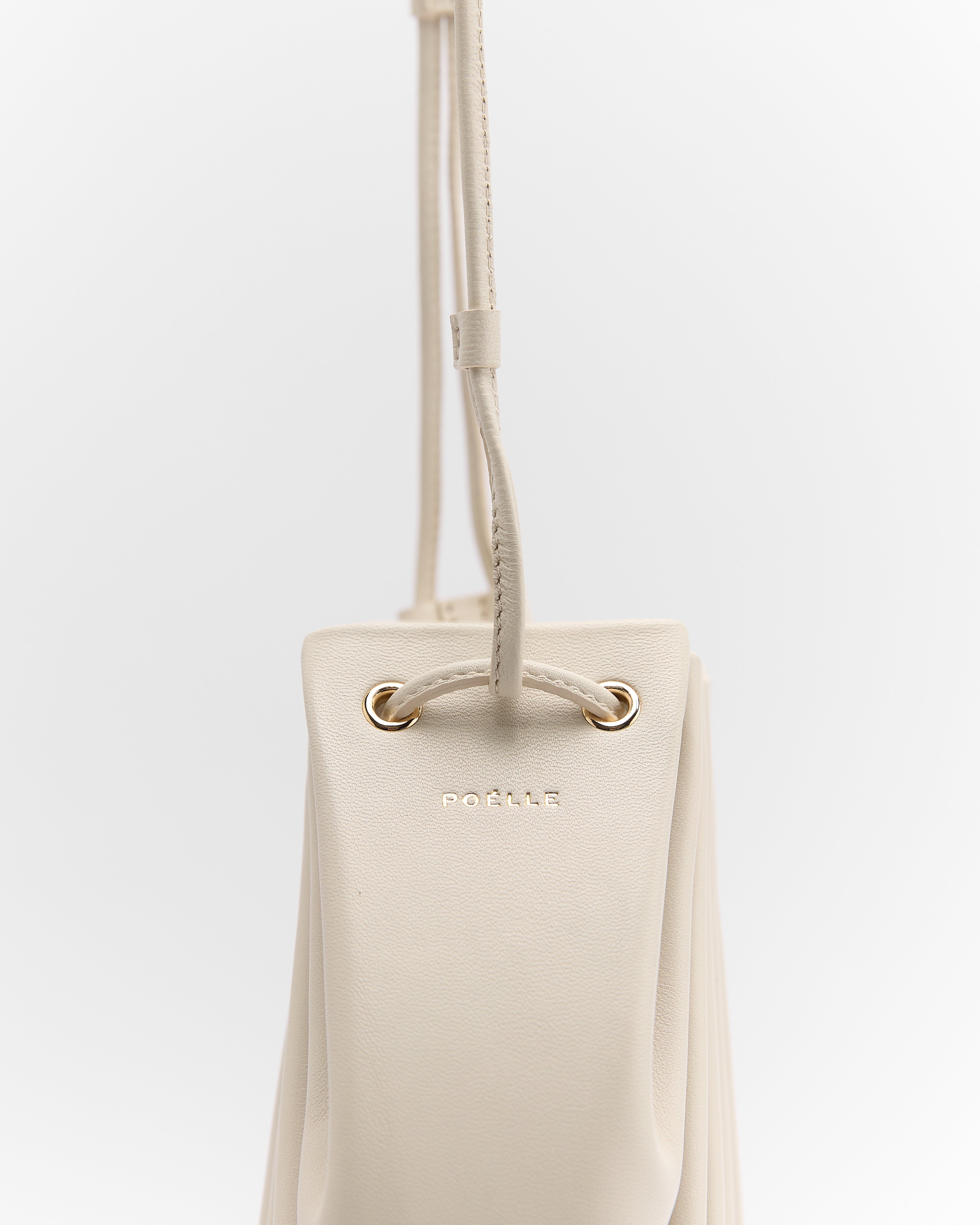 Poelle Atelier luxury summer crossbody bag in beige with gold eyelets and adjustable strap