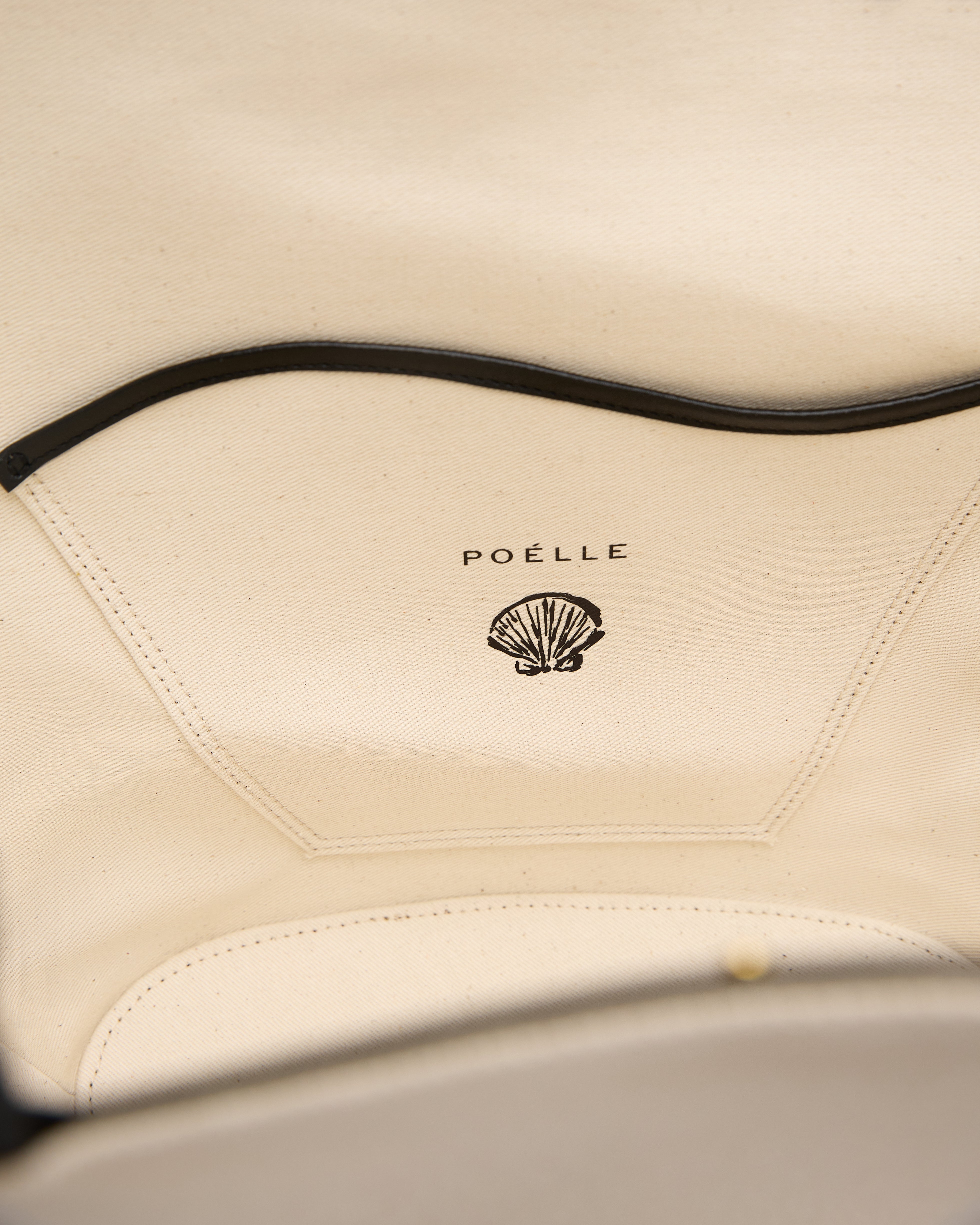 Close-up of Poelle Atelier logo inside a luxury summer leather bag with beige soft leather lining