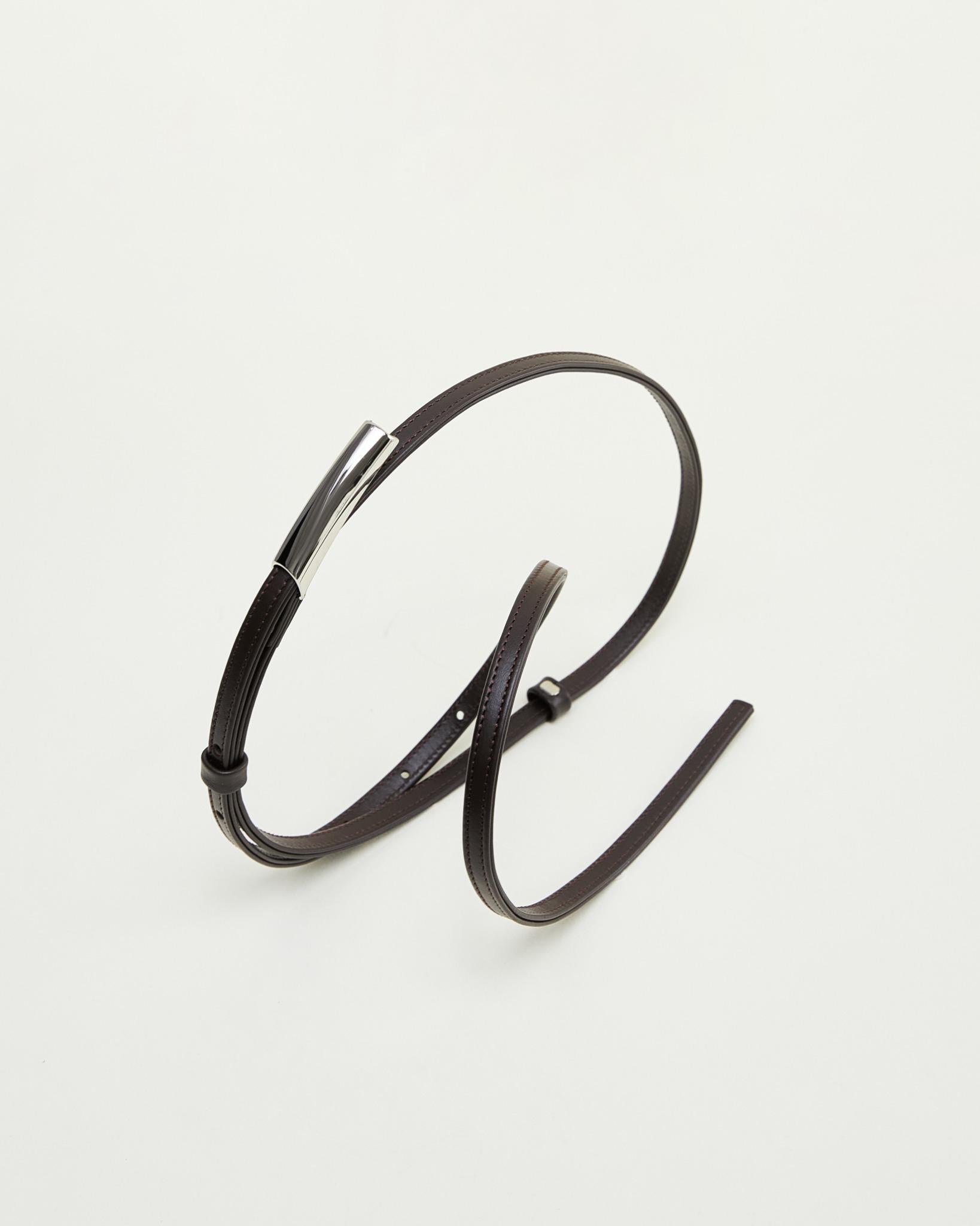 Minimalist brown leather belt by Poelle Atelier with sleek silver buckle on white background