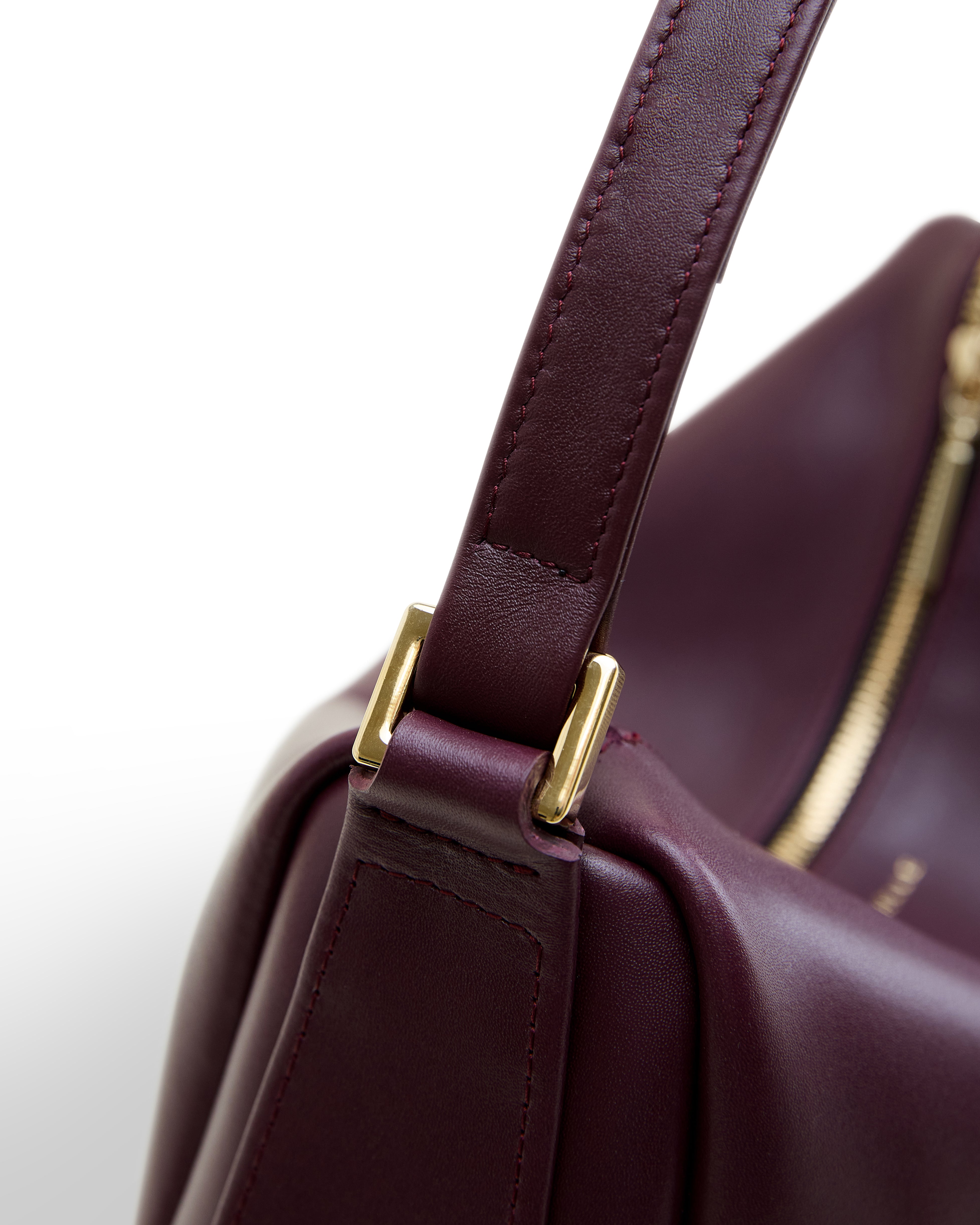 Poelle Atelier modern structured leather bag in burgundy with gold hardware close-up