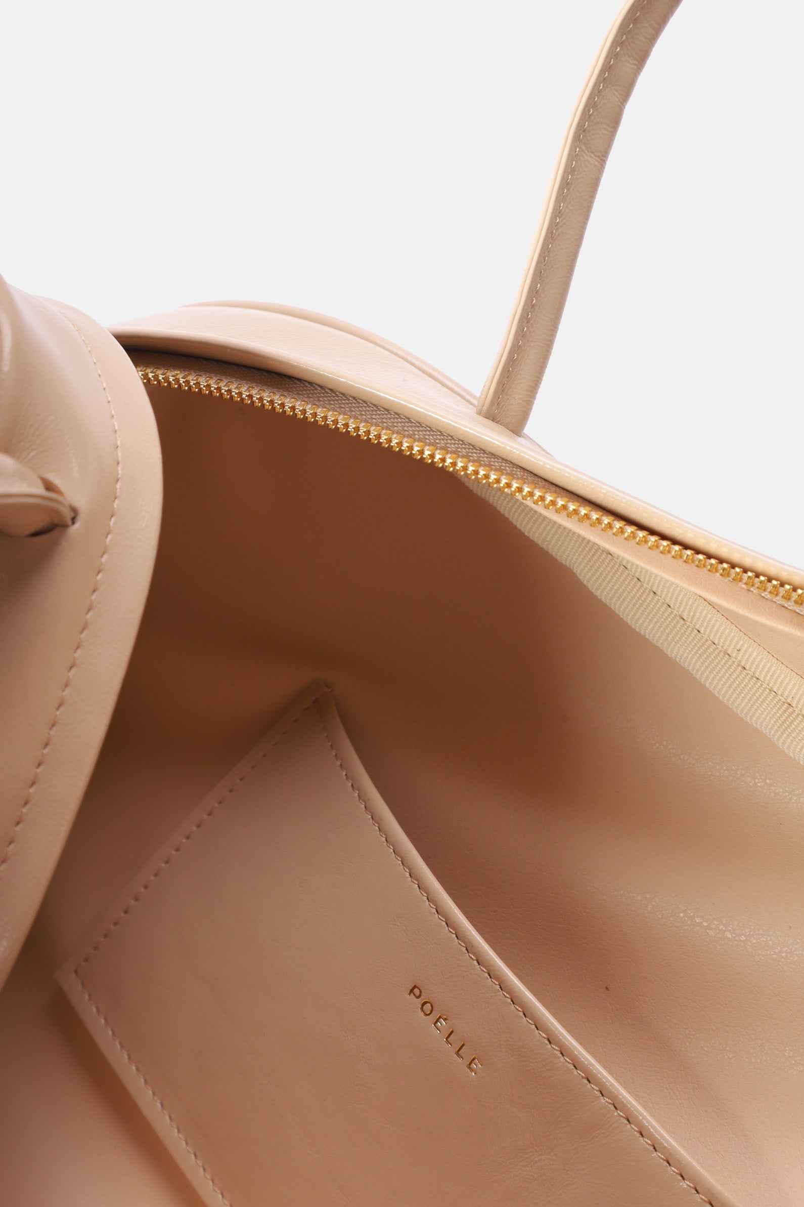 Interior view of Poelle Atelier east-west horizontal bags showing beige leather and zippered compartment