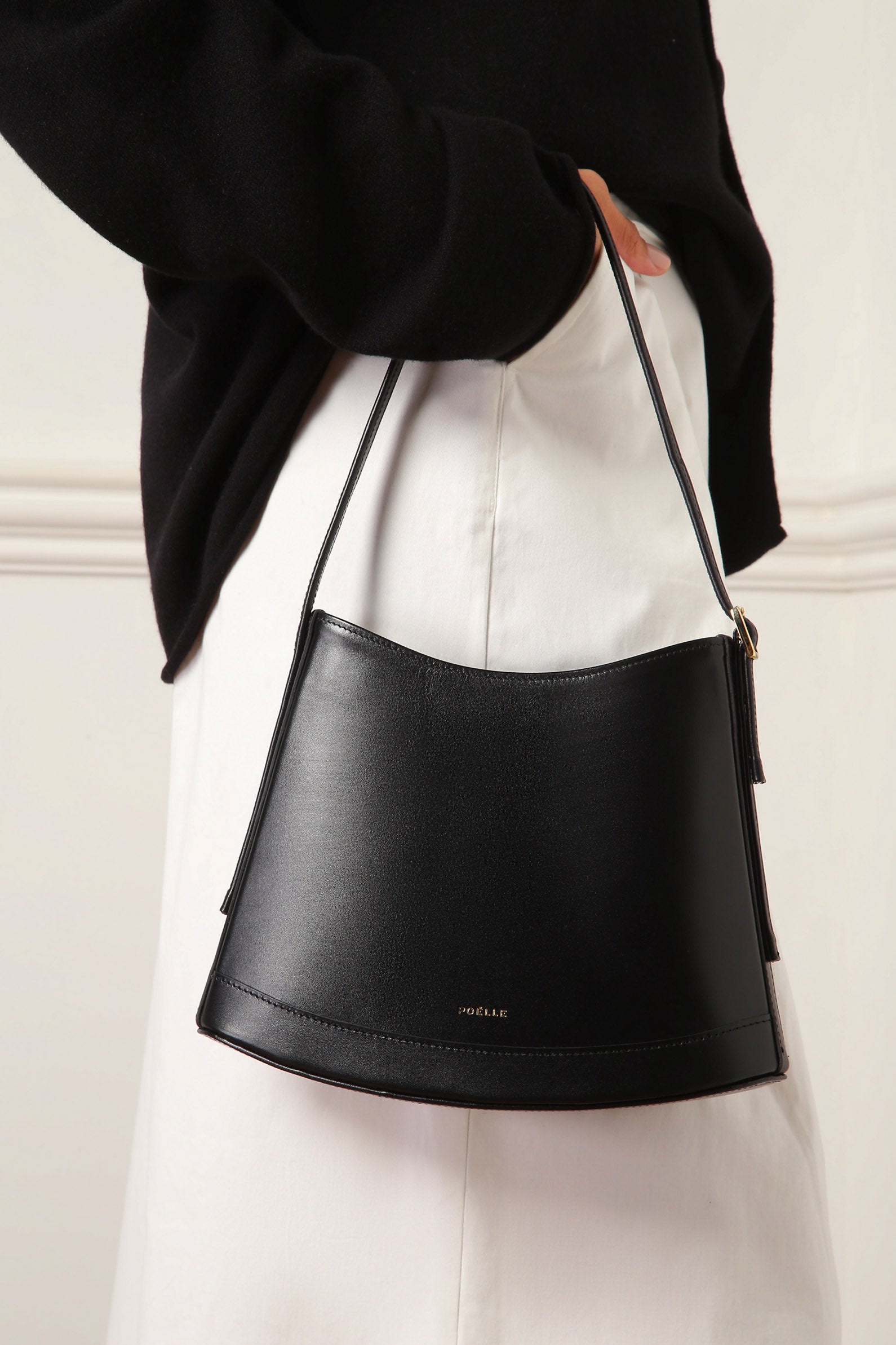Poelle Atelier luxury minimalist leather bag in black worn on shoulder with curved silhouette