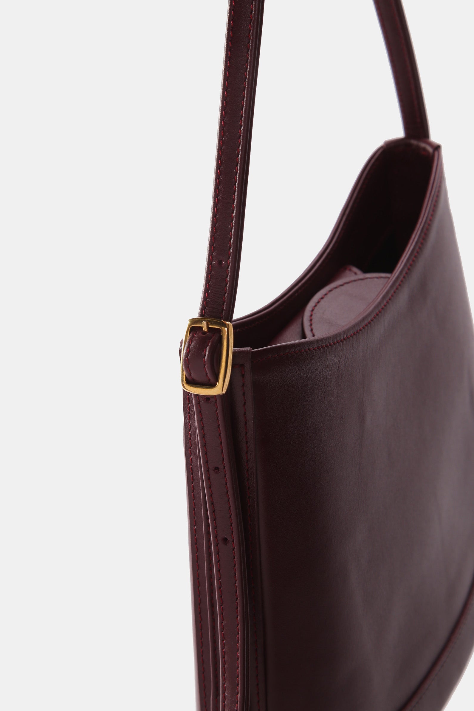 Poelle Atelier luxury minimalist leather bag in dark brown with adjustable strap and gold buckle detail