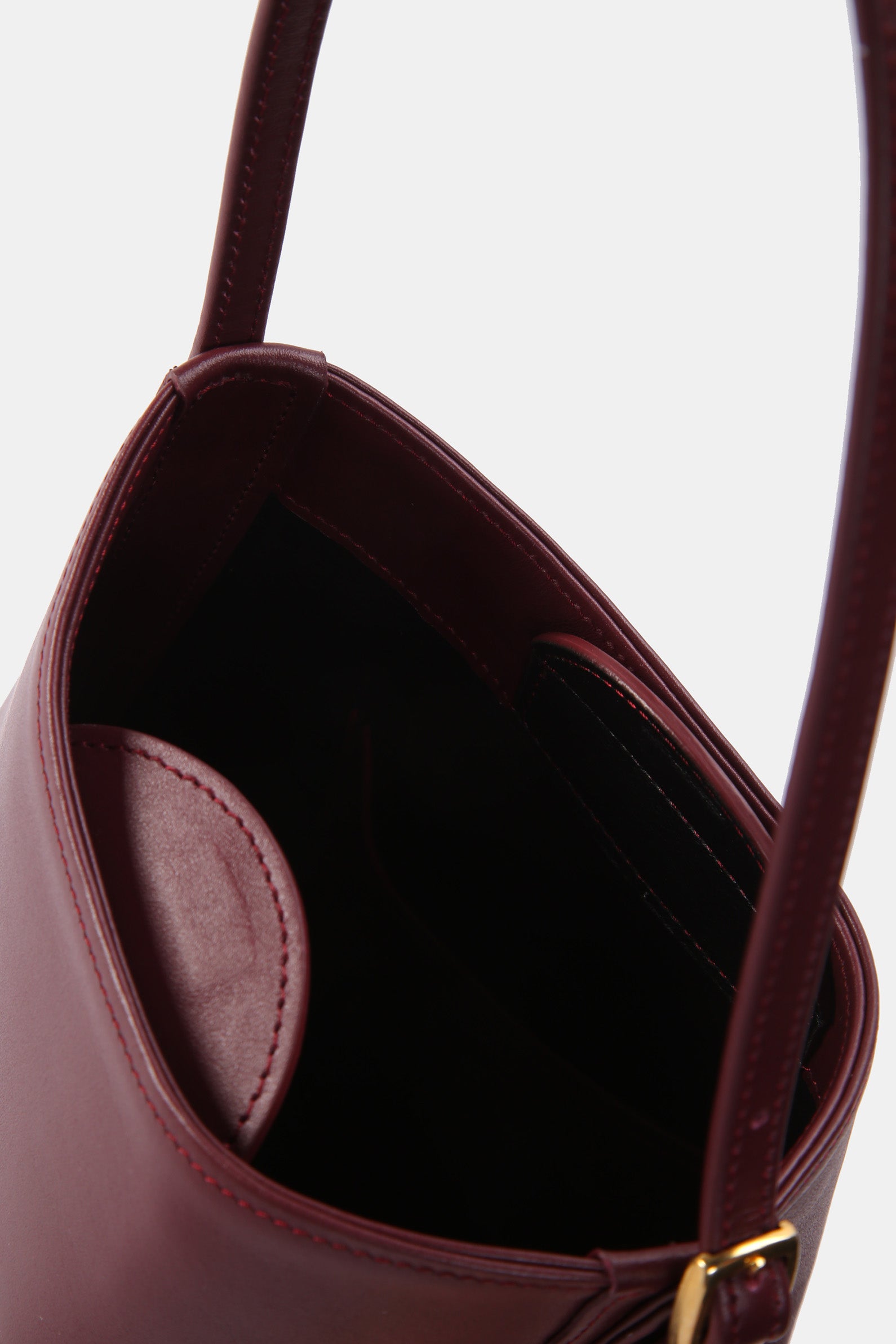 Poelle Atelier luxury minimalist leather bag in dark burgundy with smooth interior and adjustable strap