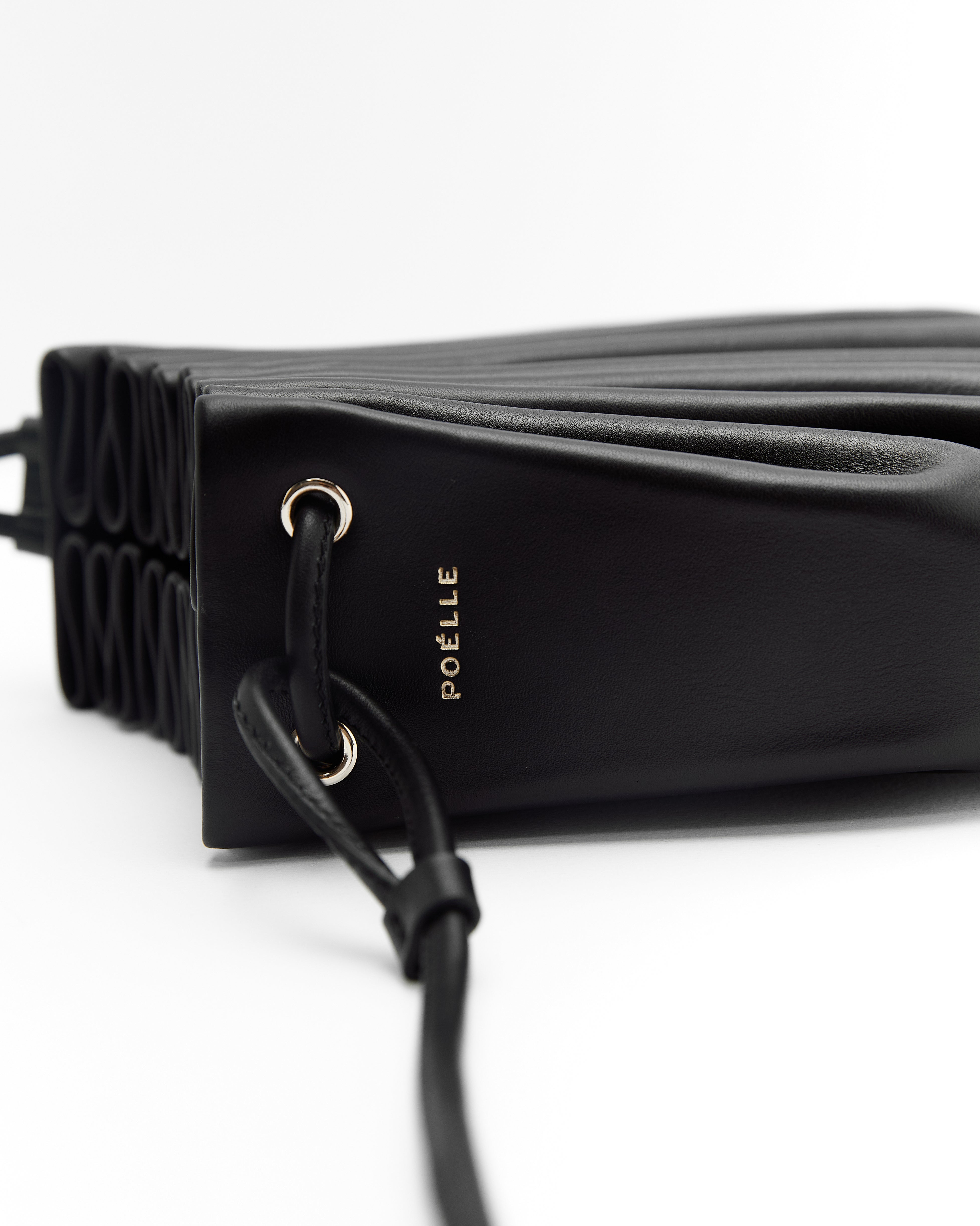 Poelle Atelier luxury summer crossbody bag in black leather with gold eyelet and adjustable strap