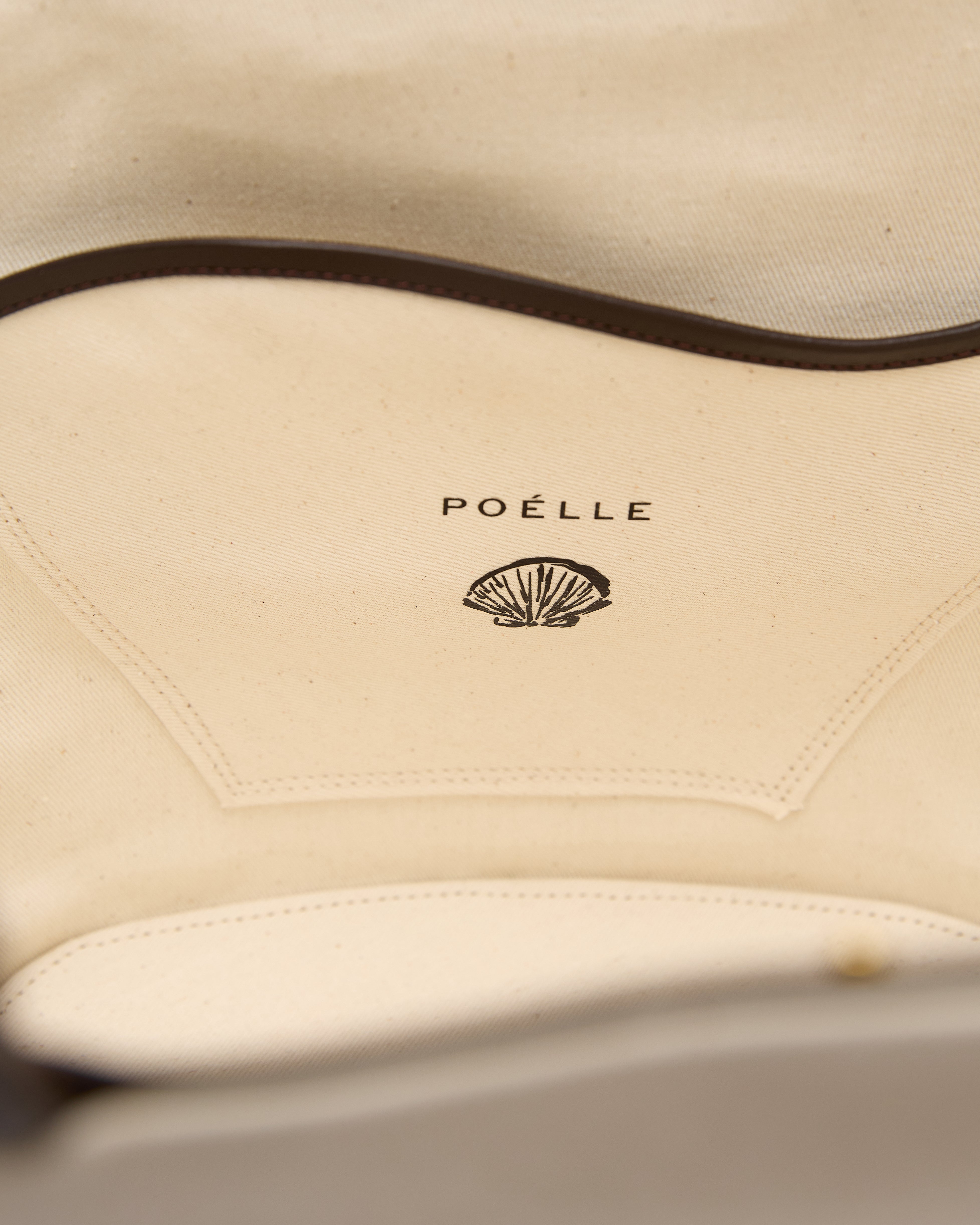 Interior view of Poelle Atelier luxury summer leather bag featuring beige lining and shell logo detail