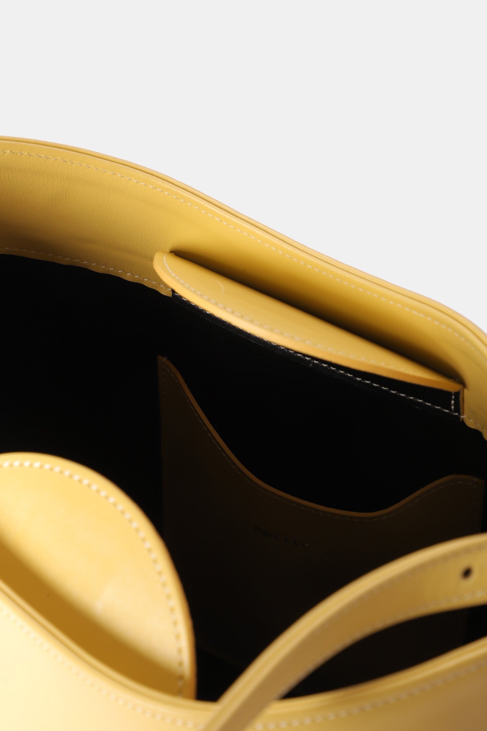Interior view of Poelle Atelier luxury minimalist sculptural bag in yellow leather with compartments