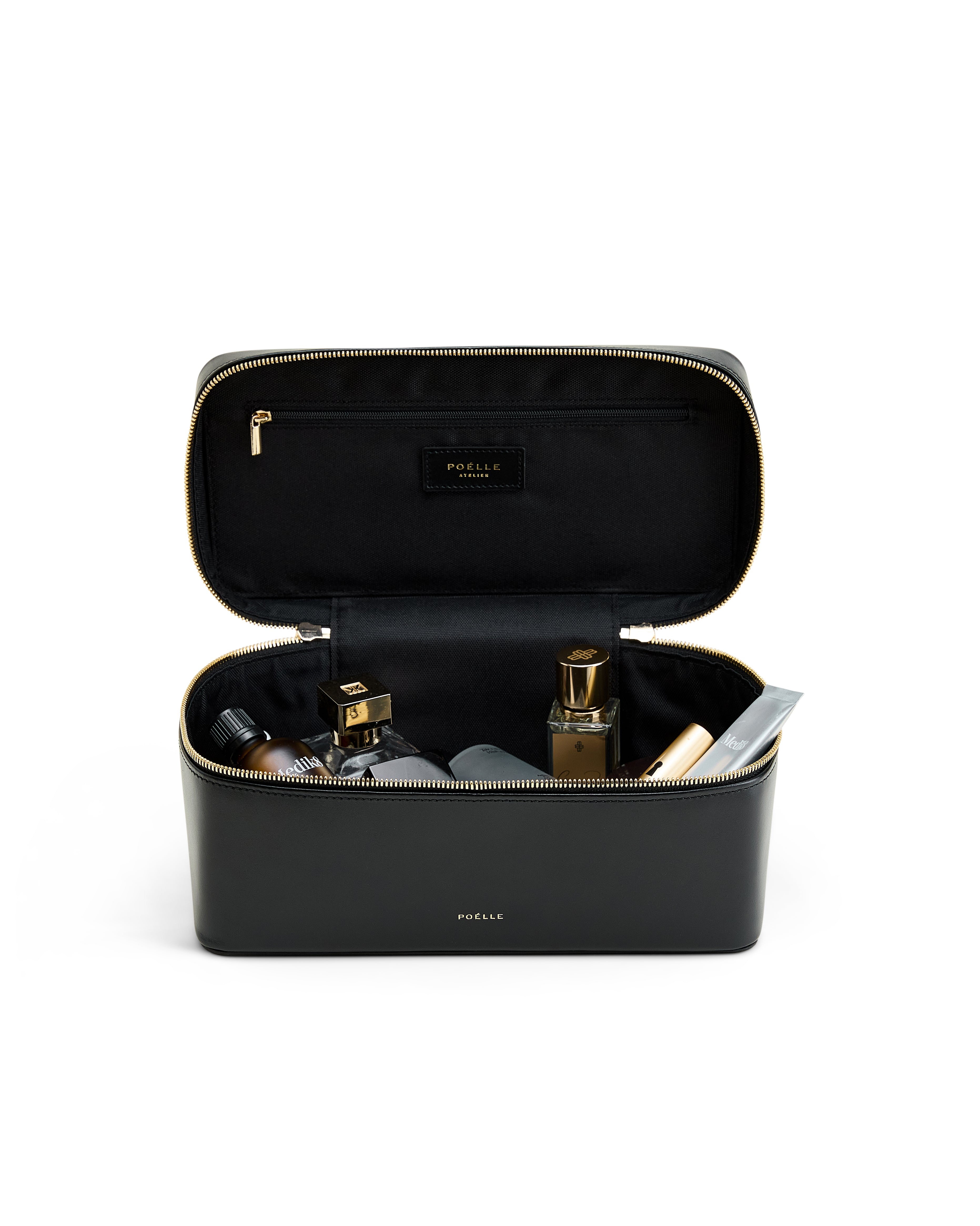 Poelle Atelier large leather makeup case in black with gold zipper and assorted cosmetics inside