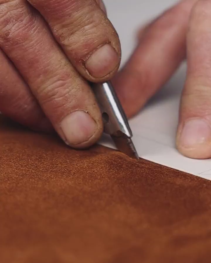 Hands tracing a pattern on suede